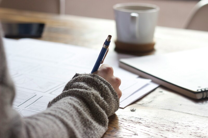 Une personne entrain d'écrire sur un cahier